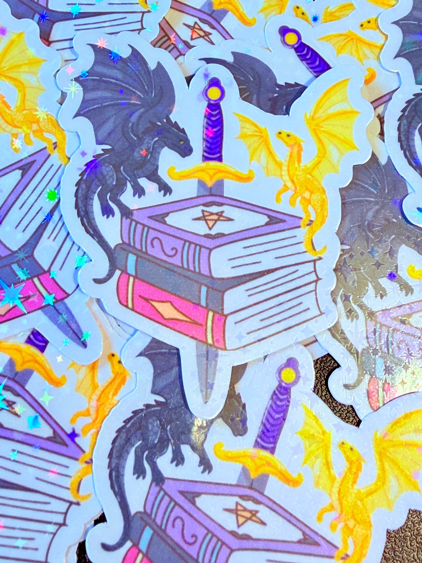 Bookish dragon sticker with sword and stacked books design