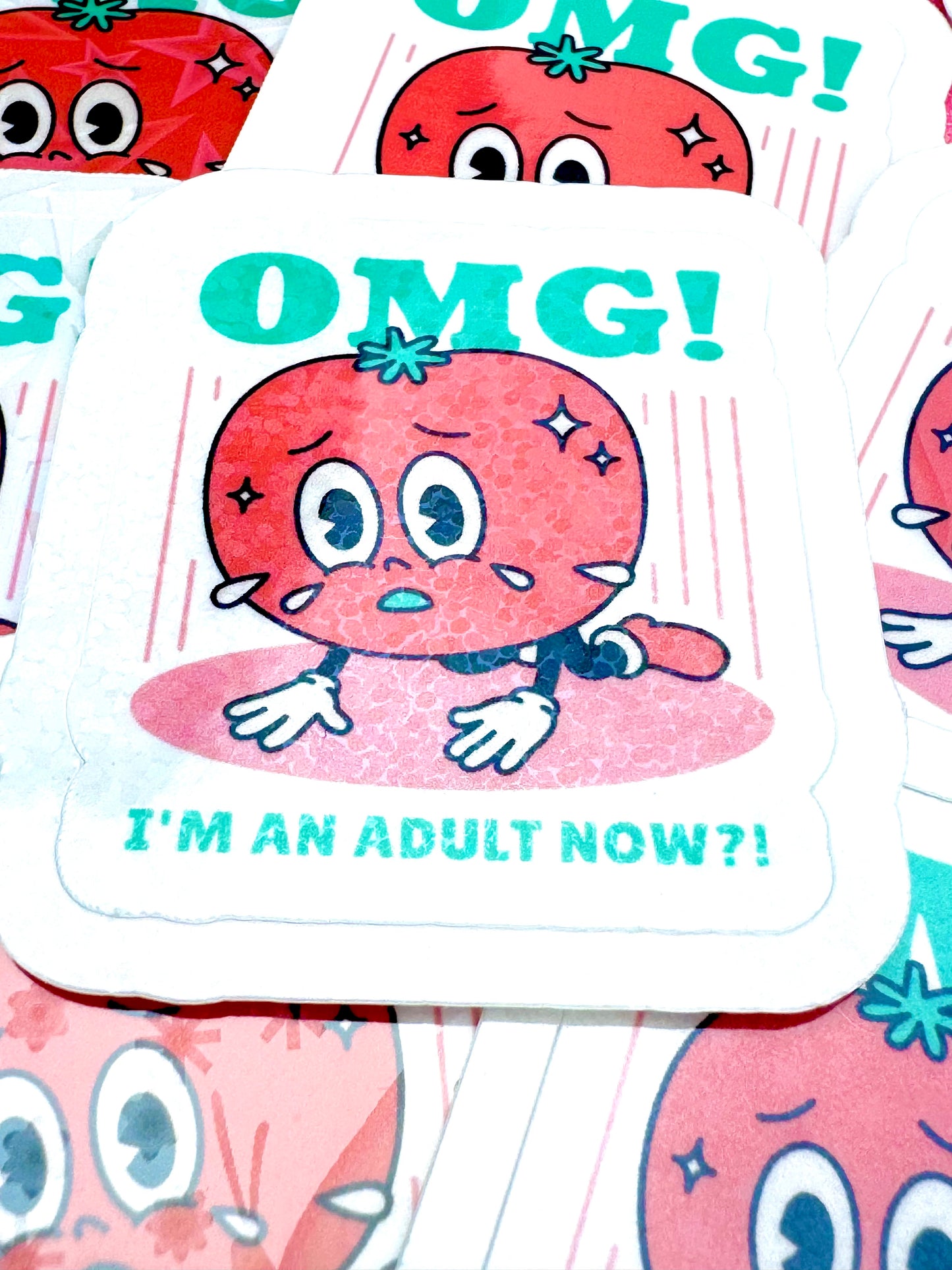 Vinyl sticker showing a cartoon tomato kneeling on the floor with sweat droplets, alongside the phrase ‘OMG! I’m an Adult Now’, photographed on a flat surface