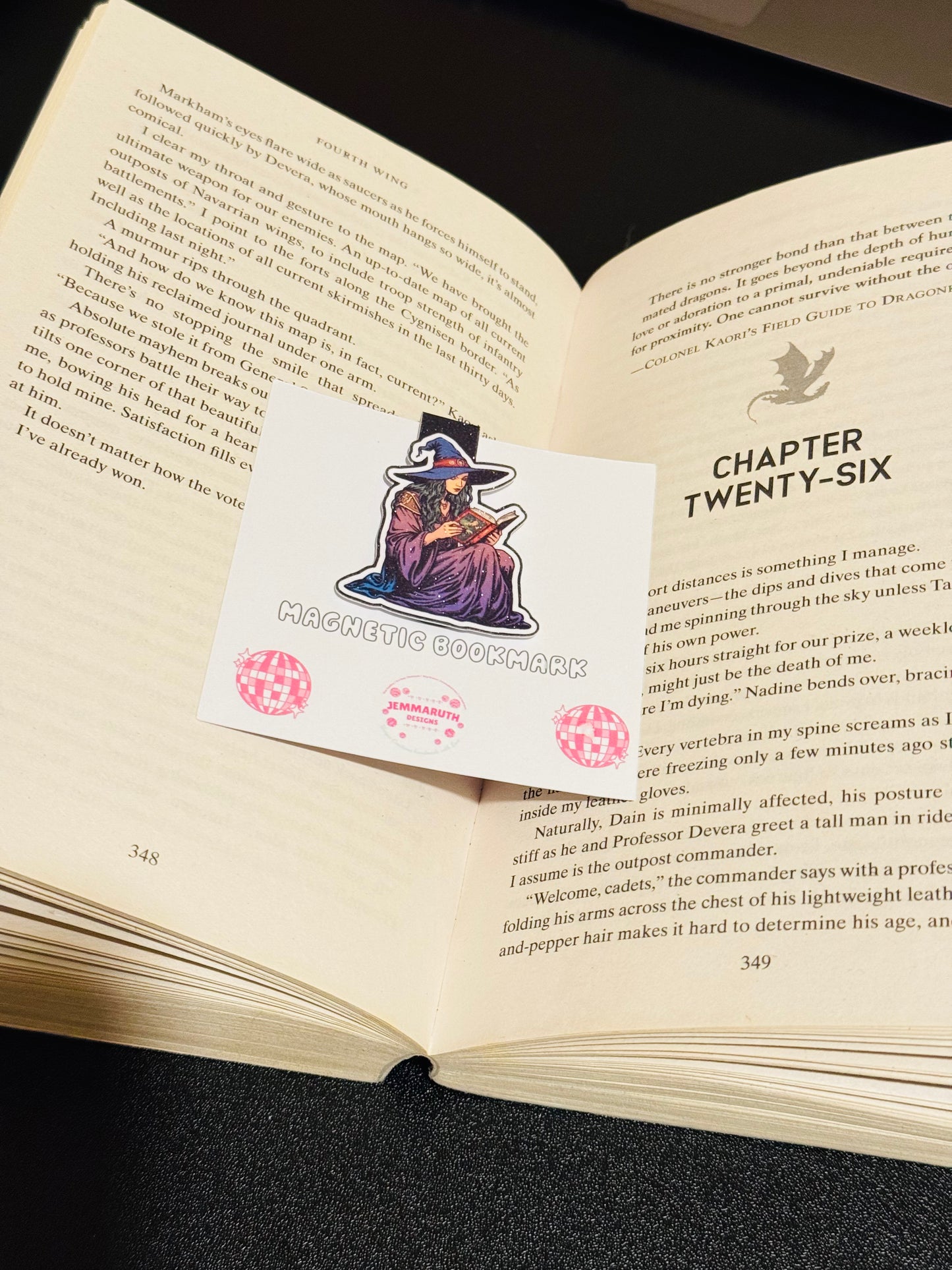 Open Book with a Witch Magnetic bookmark sitting in the middle. The witch is wearing purple and is reading a red book