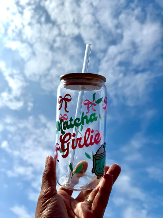 Clear 16oz glass can cup with the words ‘Matcha Girlie’, decorated with pink bows and green matcha leaves — reusable tumbler for hot or cold drinks.
