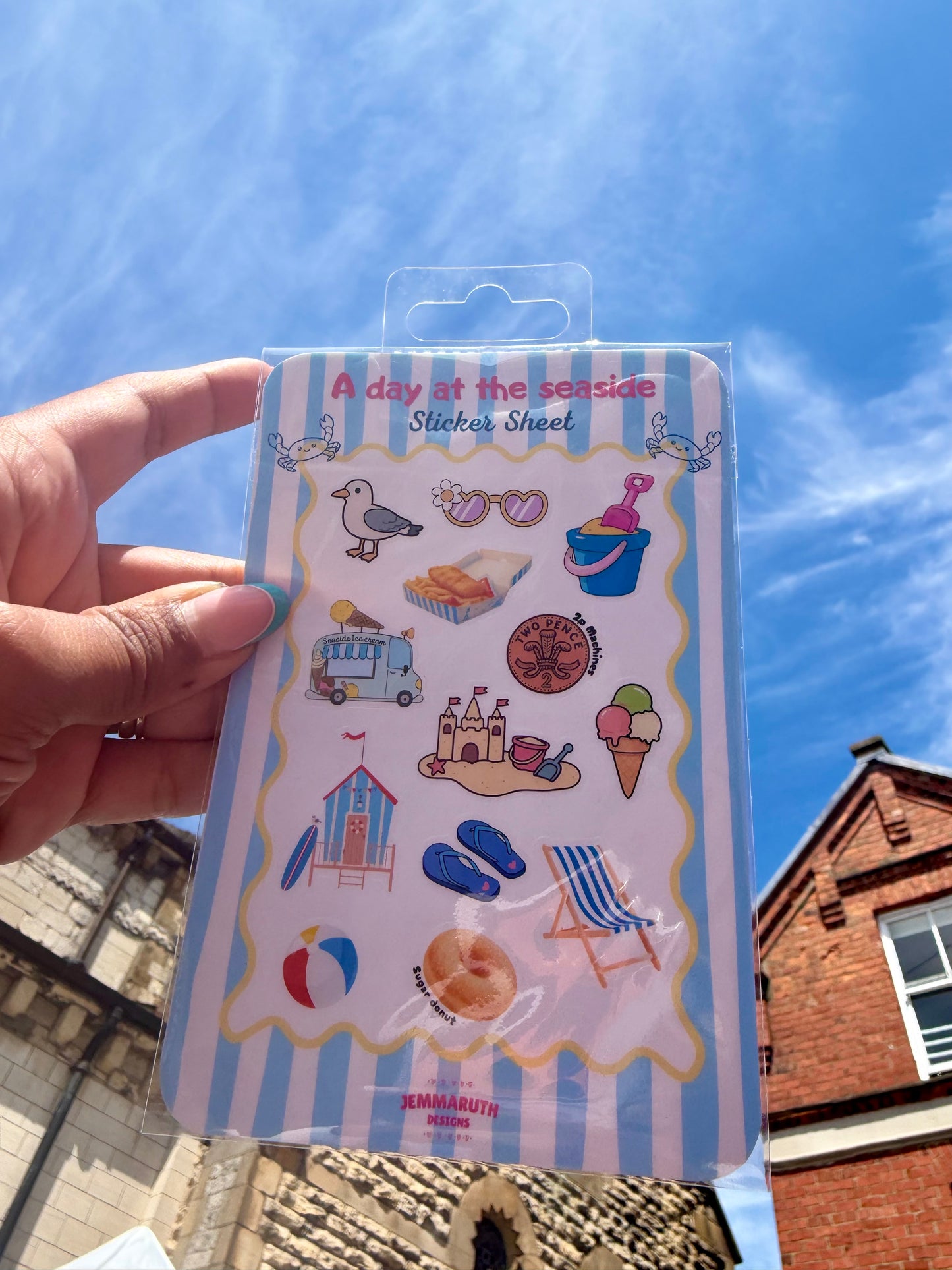 A Day at the Seaside water-resistant matte vinyl sticker sheet featuring beach-themed illustrations including a beach hut, ice cream, deckchair, fish and chips, flip flops and bucket and spade.
