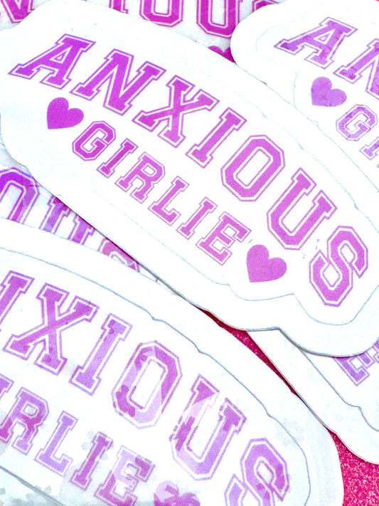 White vinyl sticker with the phrase ‘Anxious Girlie’ in lilac font, photographed on a flat surface.