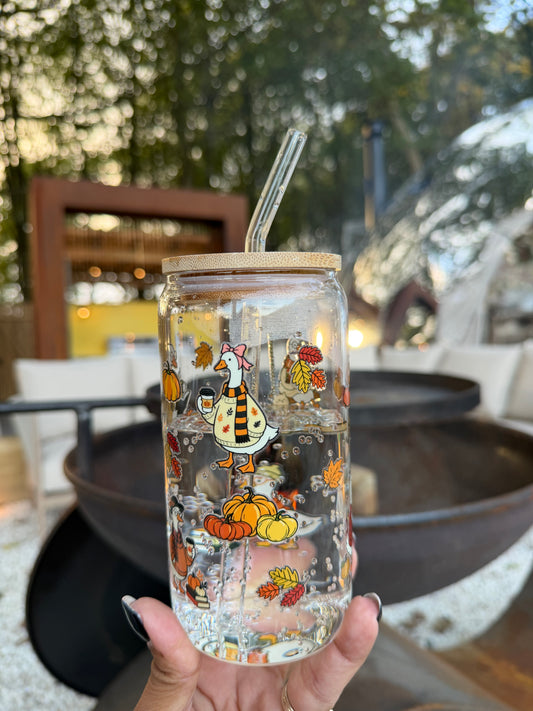 Autumn Days glass can cup featuring a cute goose wearing a scarf, pumpkins and colourful autumn leaves, with a bamboo lid and glass straw.