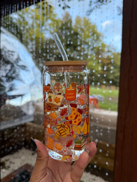 Cosy Nights glass can cup featuring autumn leaves, cosy socks, books, candles and warm seasonal illustrations with a bamboo lid and glass straw.