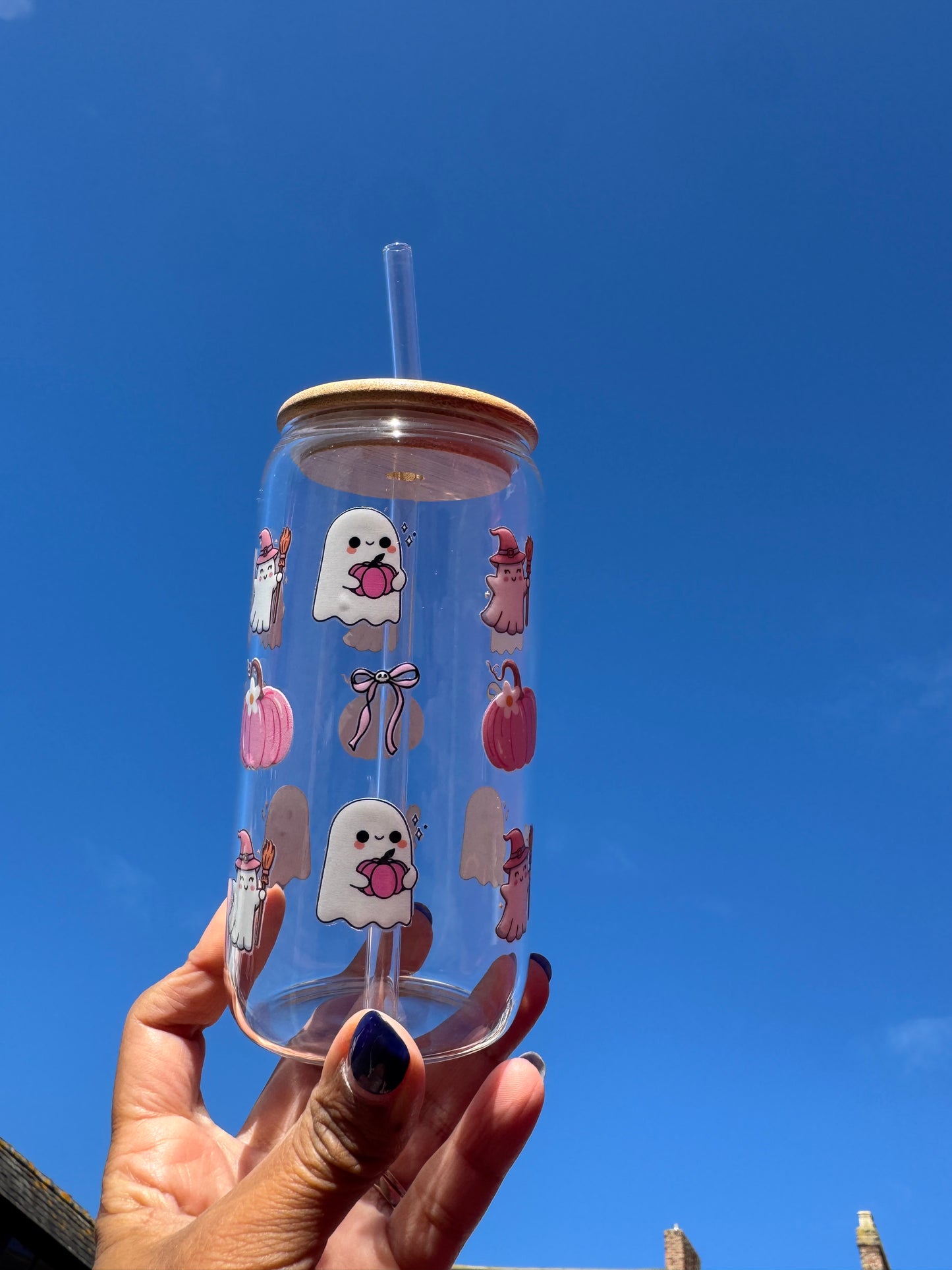"A clear glass can cup with a spooky-cute Halloween design: a boo ghost holding a pink pumpkin, pink bows with skulls, pink pumpkins, and a ghost witch."