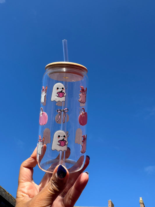 "A clear glass can cup with a spooky-cute Halloween design: a boo ghost holding a pink pumpkin, pink bows with skulls, pink pumpkins, and a ghost witch."