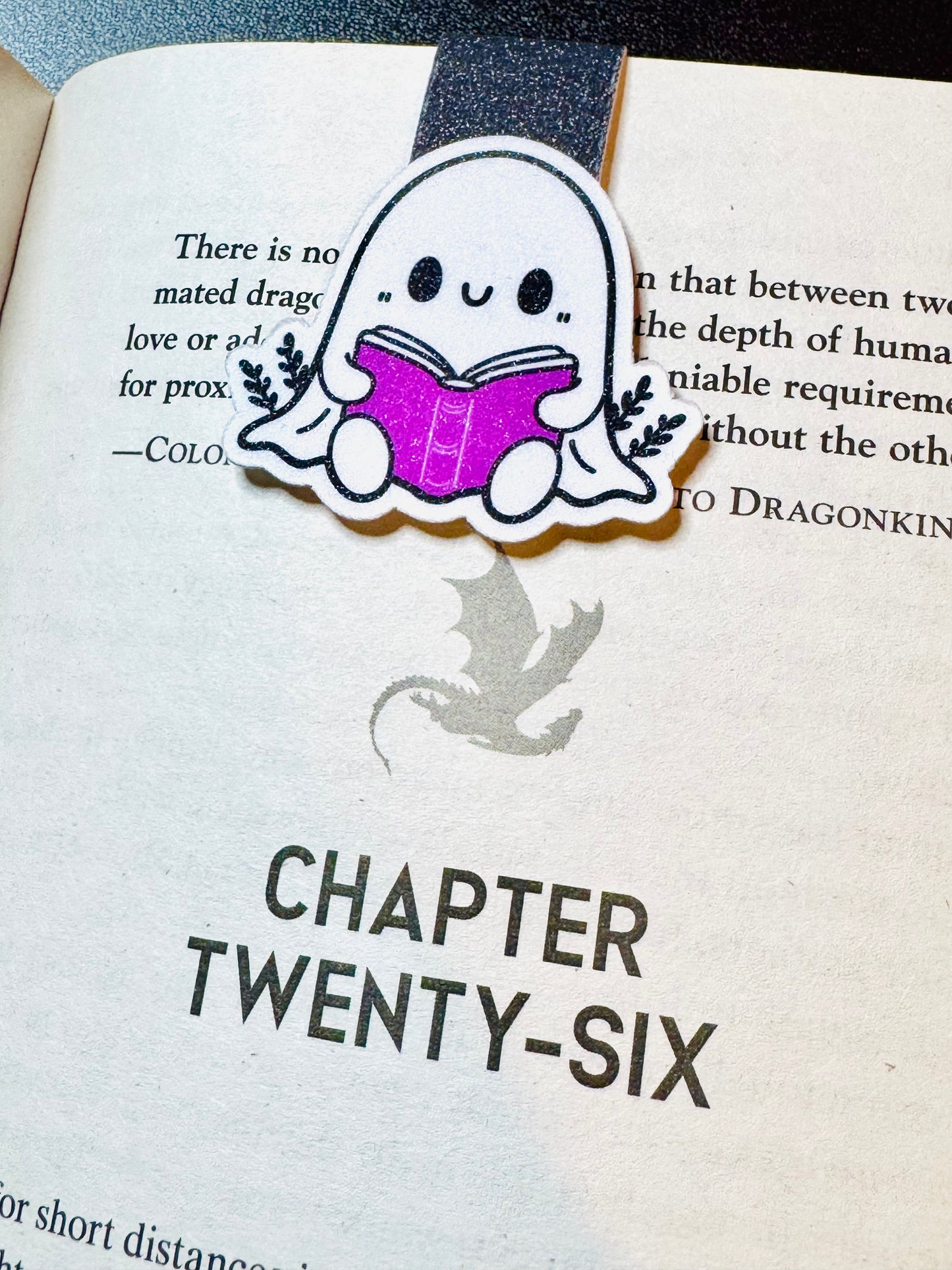 Book Ghost reading a Purple Book, hanging on the page of a book.