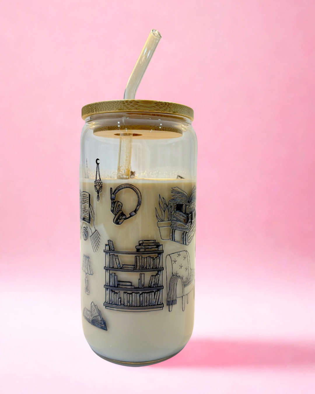 Bookish glass can cup featuring stacked books, black cat, e-reader and open book illustrations with bamboo lid and glass straw