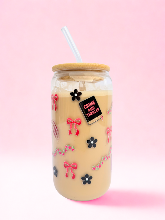 A 16oz glass with a bamboo lid and glass straw, featuring red bows, black flowers, and a “Crime and Thriller” design on a pink background. Matching bookmark sold separately.
