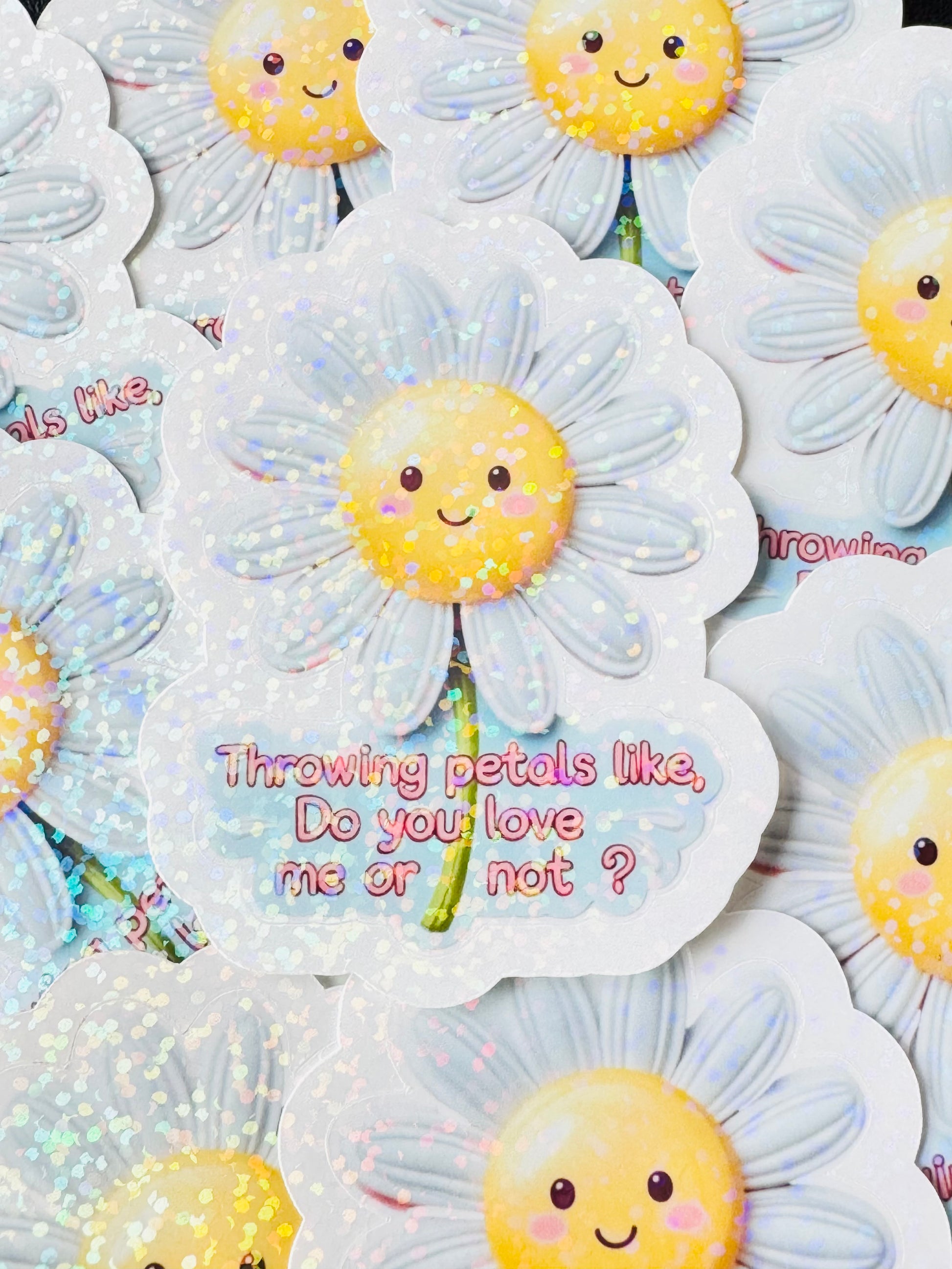 Cute waterproof vinyl sticker of a smiling daisy tossing petals with the quote “Throwing petals like, do you love me or not” – inspired by Justin Bieber’s Daisies song. Glossy overlay finish.