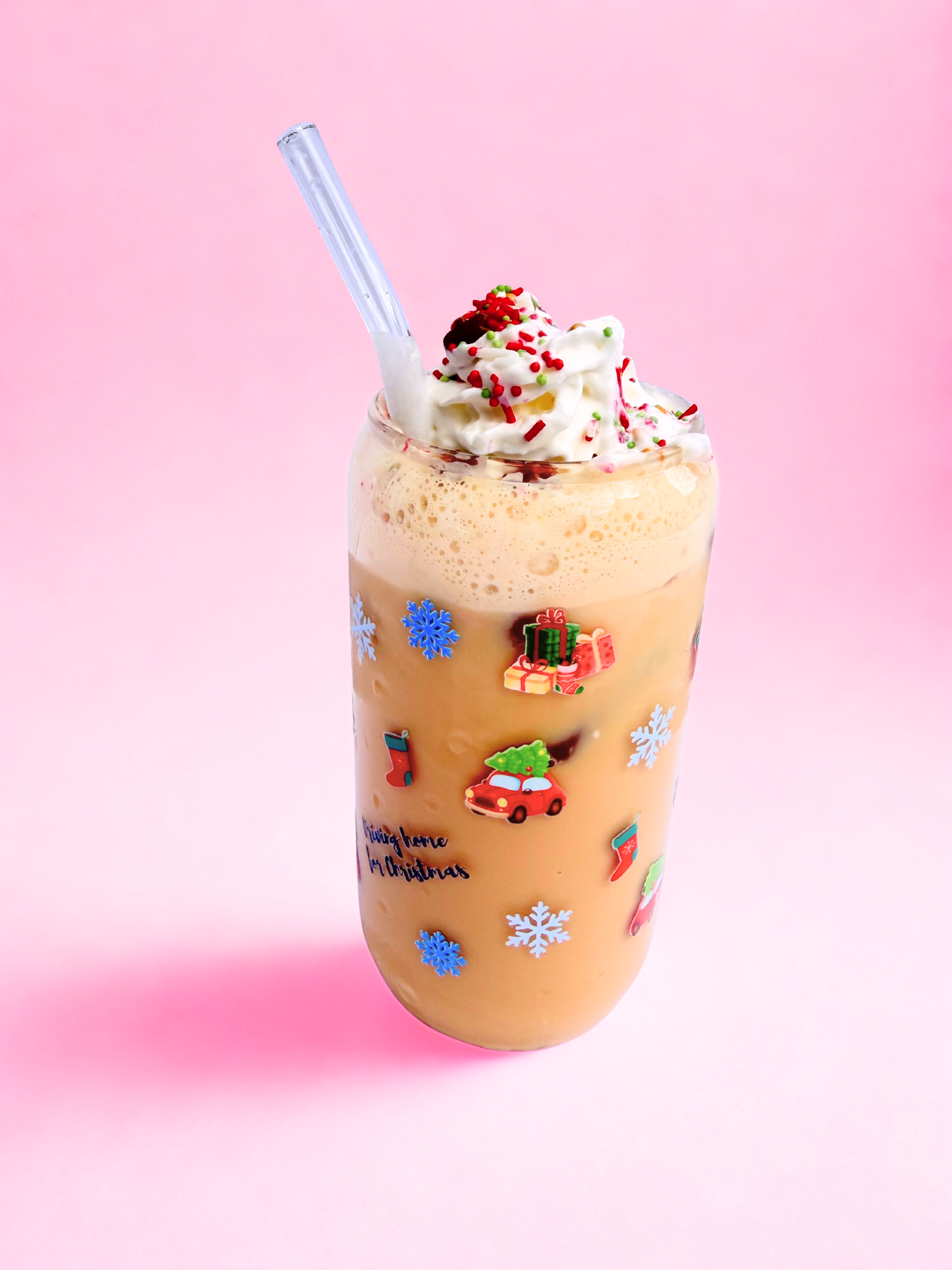 Glass Can Cup with driving home for christmas written on it, images showing car with a christmas tree o the roof, snowflakes and presents, on a pink background