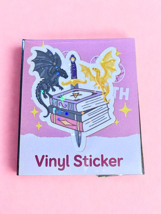 Fantasy dragon vinyl sticker with black and gold dragons on stacked books, holographic stars and glossy laminate finish.