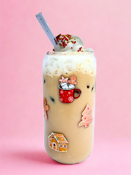 Glass can cup with gingerbread man, gingerbread house, and ginger bread christmas tree images on the glass, on a pink background