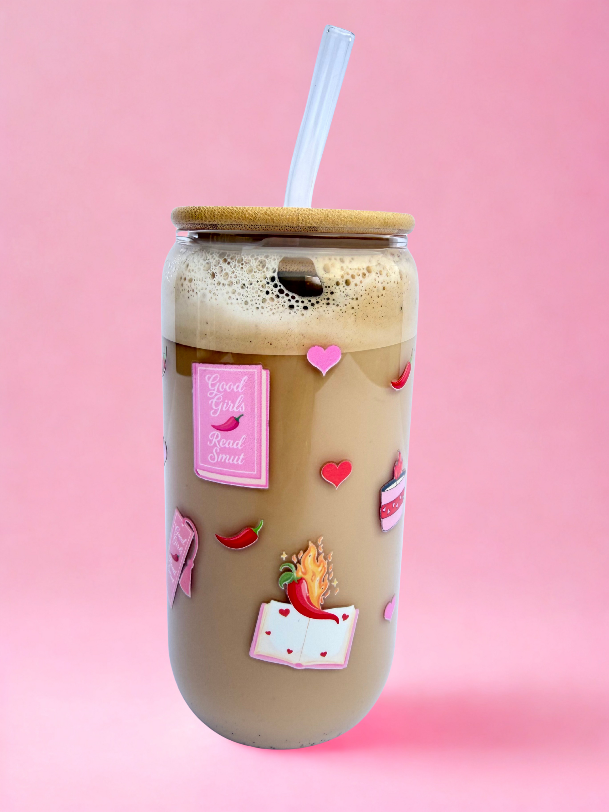 A 16oz glass with a bamboo lid and glass straw, featuring pink “Spicy Book Club” and “Good Girls Read Smut” designs with hearts and chilli peppers, on a pink background. Matching bookmark sold separately.