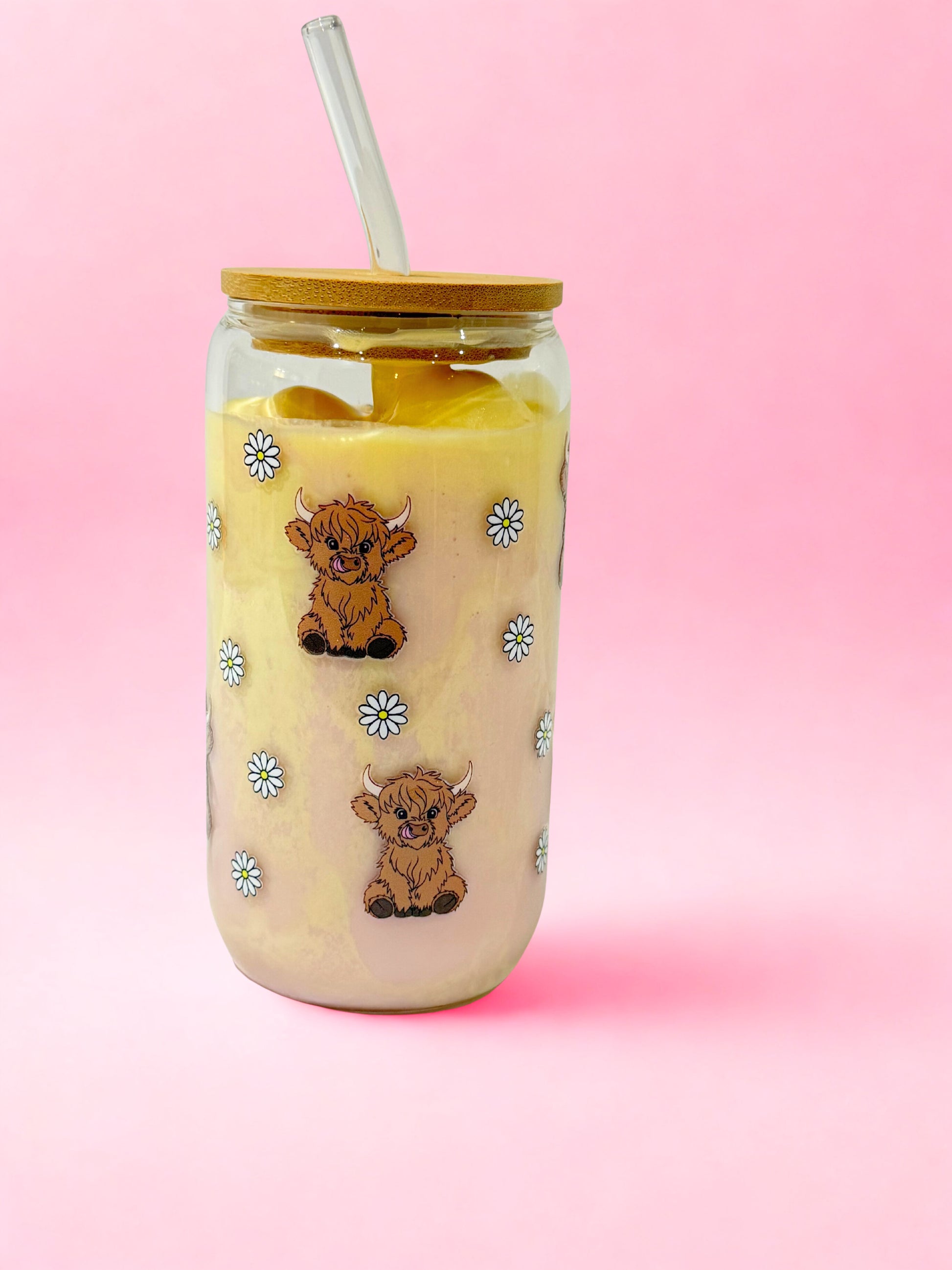 “16oz highland cow glass can cup with bamboo lid and glass straw, cute cow and daisy design on a pink background.”