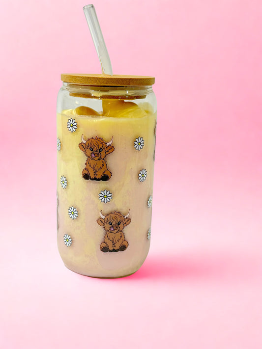 “16oz highland cow glass can cup with bamboo lid and glass straw, cute cow and daisy design on a pink background.”