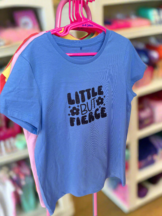 A blue kids' T-shirt with the text 'LITTLE BUT FIERCE' printed in bold letters, displayed on a hanger.