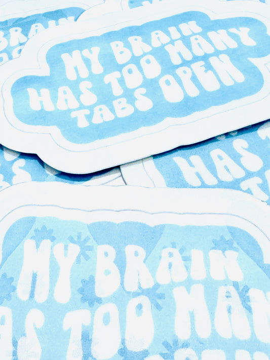 White vinyl sticker with the phrase ‘My Brain Has Too Many Tabs Open’ in baby blue font, photographed on a flat surface.