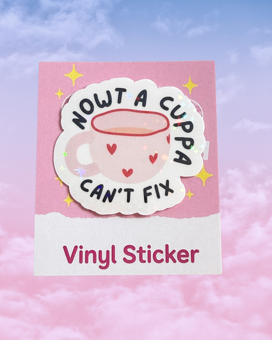A vinyl sticker featuring a cute pink cup with a halo and the text 'NOWT A CUPPA CAN'T FIX' in black, shown on its pink backing card with 'Vinyl Sticker' printed at the bottom against a pastel pink and blue sky background.