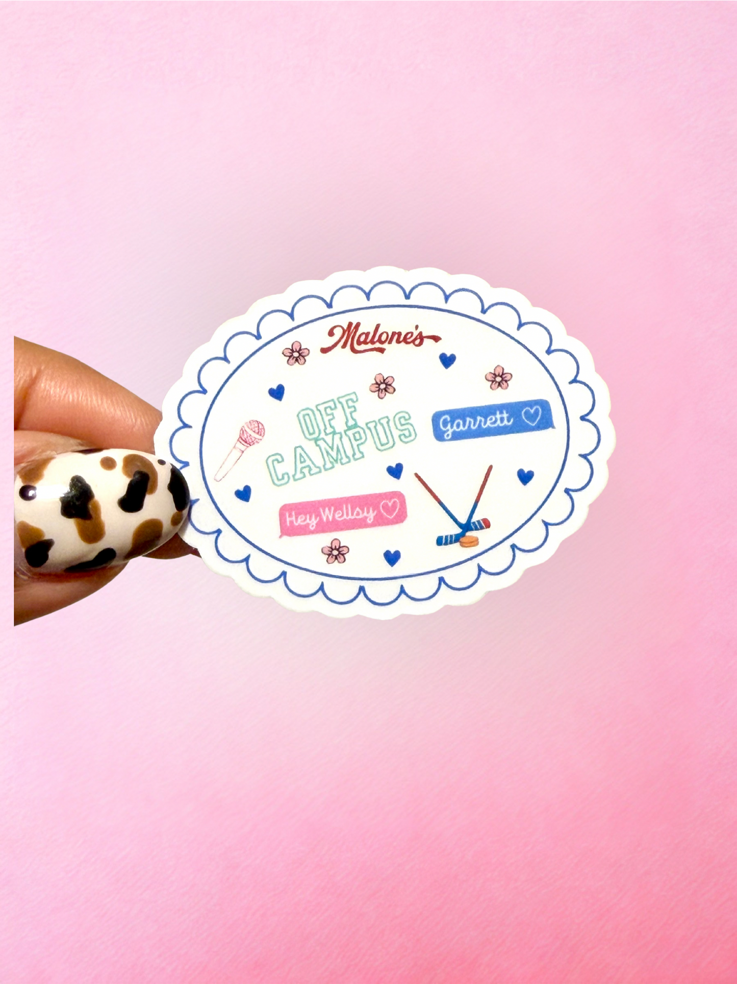 Off Campus inspired handmade vinyl sticker with pastel hockey romance themed artwork including Garrett, Hey Wellsy text, hearts, flowers and hockey sticks on a white scalloped oval design.