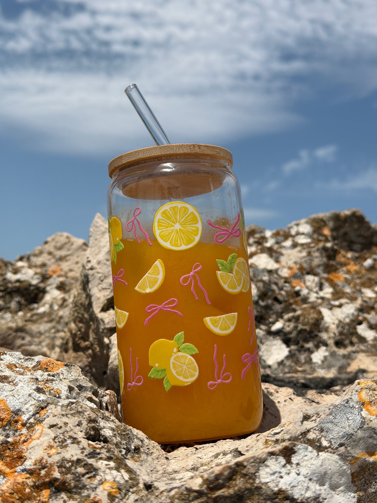 Pink Bows & Lemons Glass Can Cup styled on coastal rocks with lemon illustrations and pink bows.