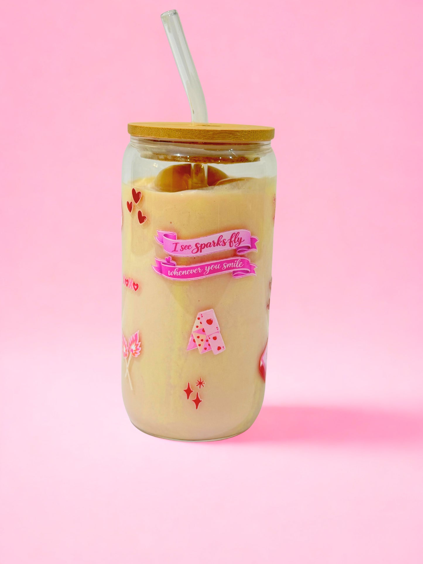 “16oz clear glass can cup with bamboo lid and glass straw, featuring a pink Valentine’s design inspired by ‘Sparks Fly’ with hearts, love notes and romantic details on a pink background.”