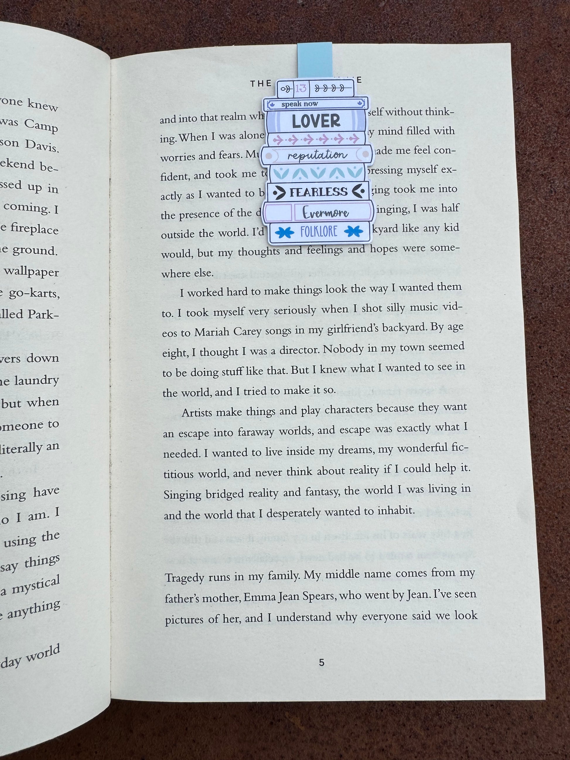 Magnetic bookmark is sat on the page of a book the design is a stack o books with swift album titles on the books