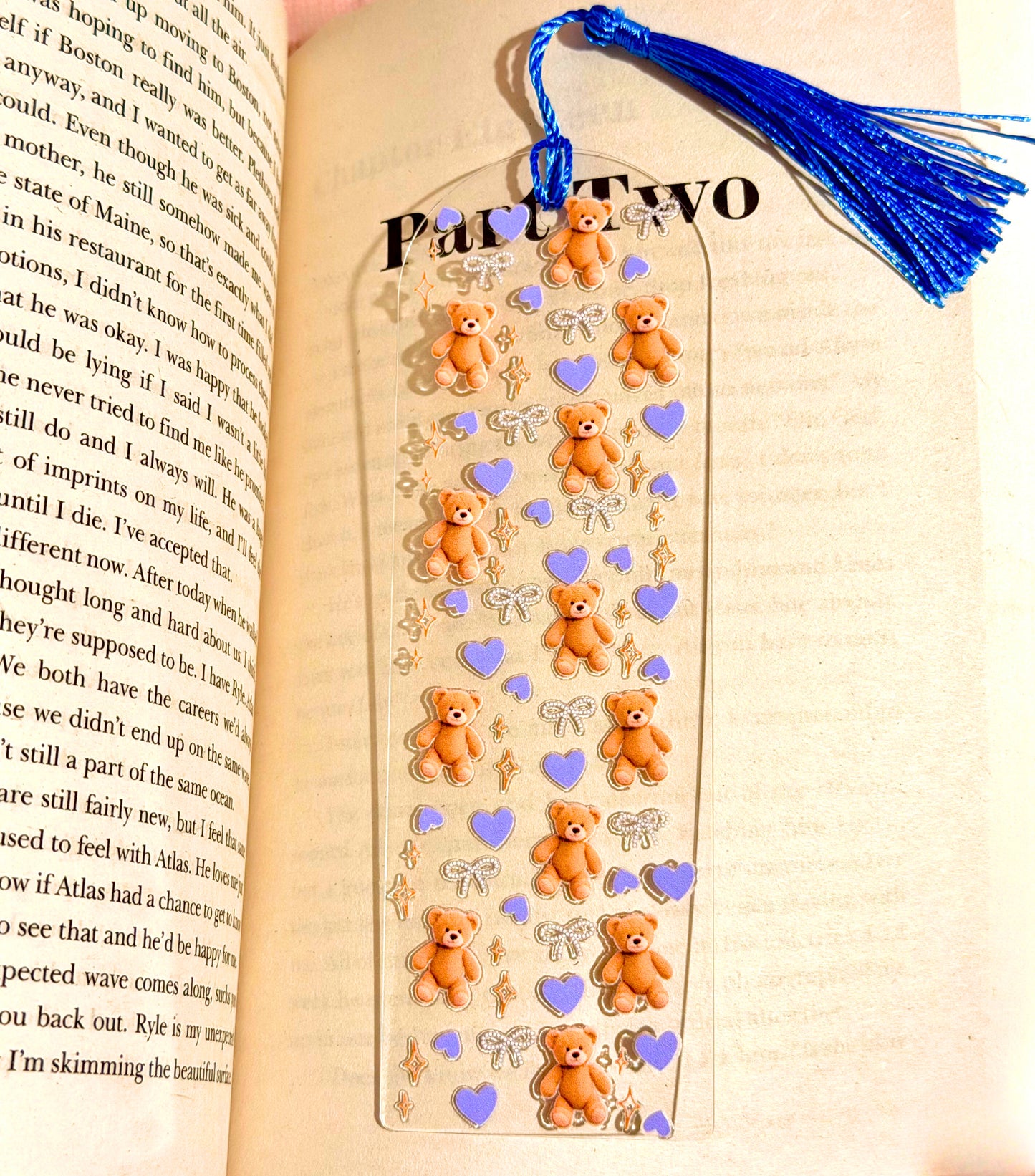 Teddy bear acrylic bookmark with tassel placed inside an open book