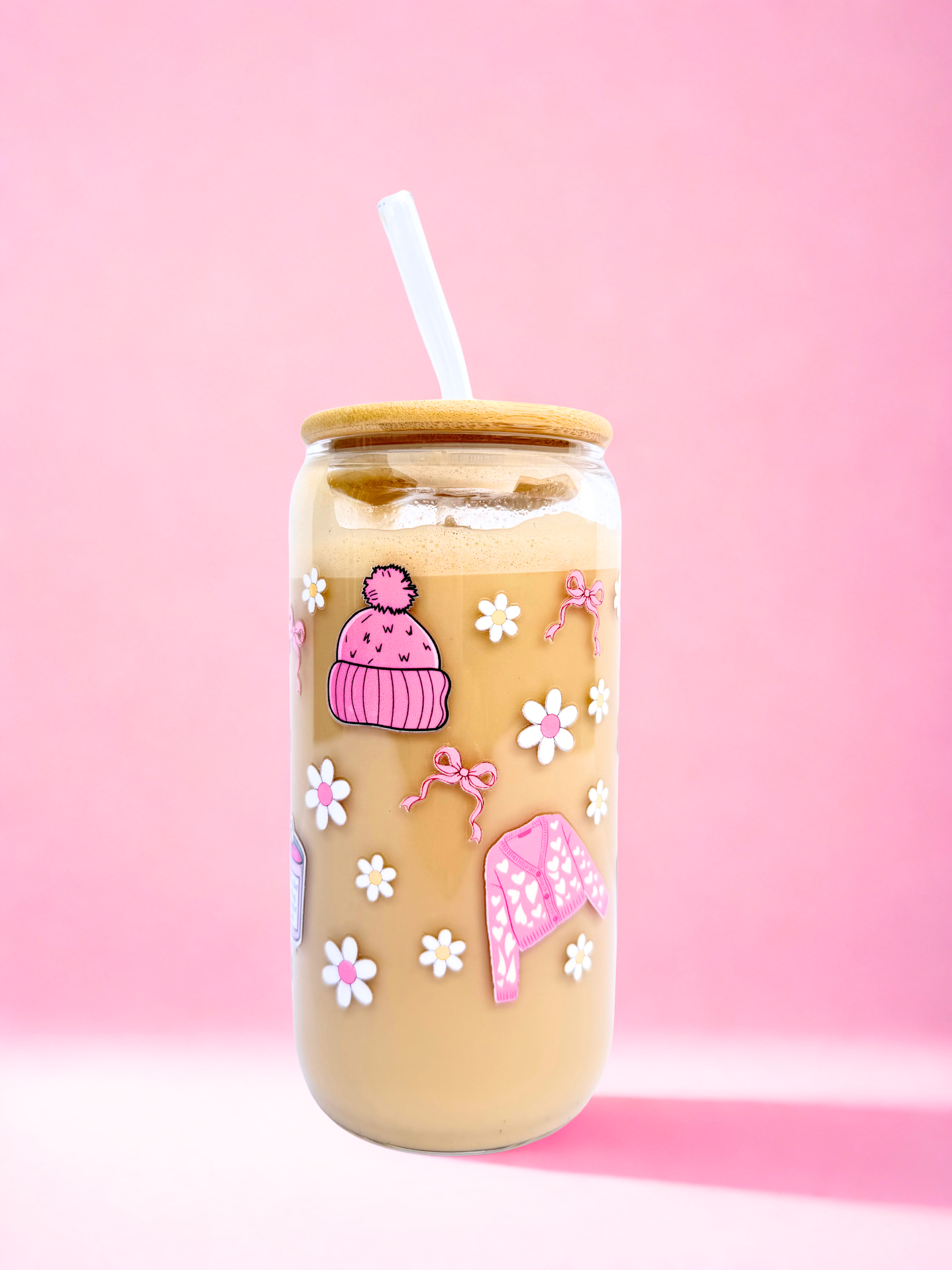 A 16oz glass with a bamboo lid and glass straw, decorated with pink bows, daisies, boots, jumpers, and a candle that says “Smells like reading romance again” on a pink background. Matching bookmark sold separately.