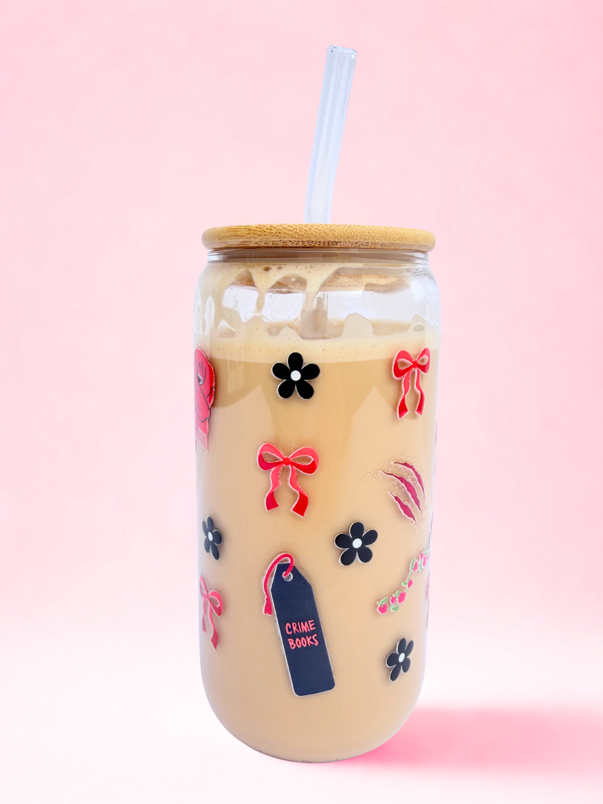 A 16oz glass with a bamboo lid and glass straw, featuring red bows, black flowers, and a “Crime and Thriller” design on a pink background. Matching bookmark sold separately.