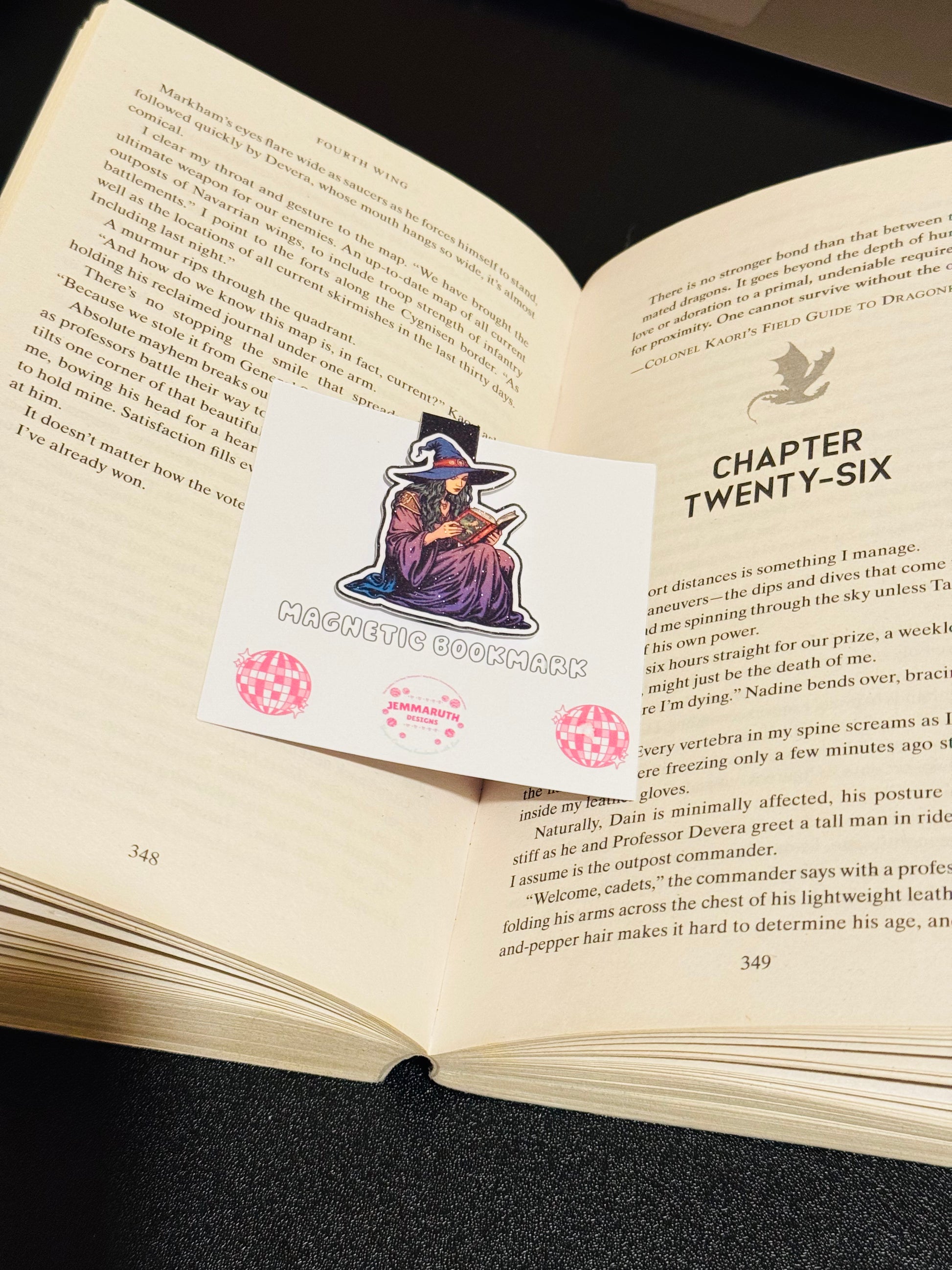 Open Book with a Witch Magnetic bookmark sitting in the middle. The witch is wearing purple and is reading a red book