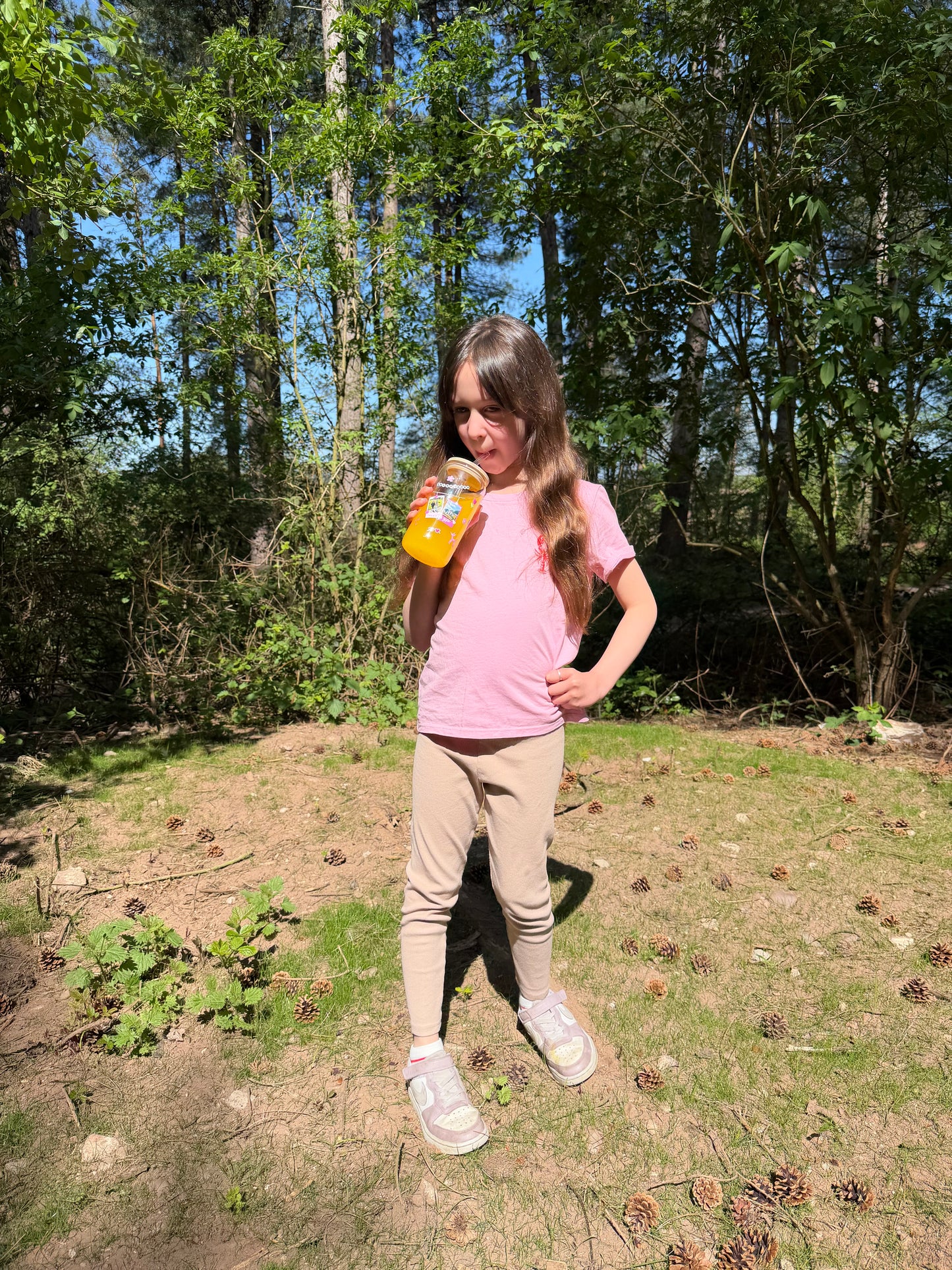 Girl holding a personalised friendship bracelet glass can cup, in the forest