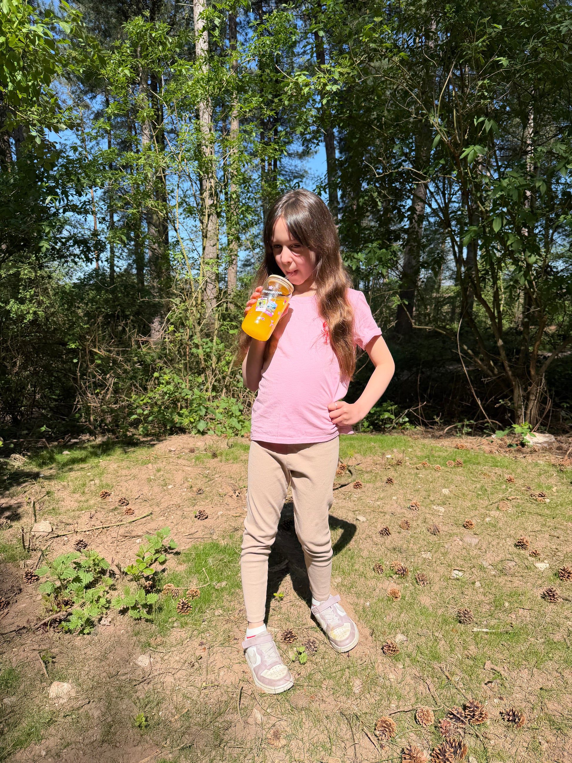 Girl holding a personalised friendship bracelet glass can cup, in the forest