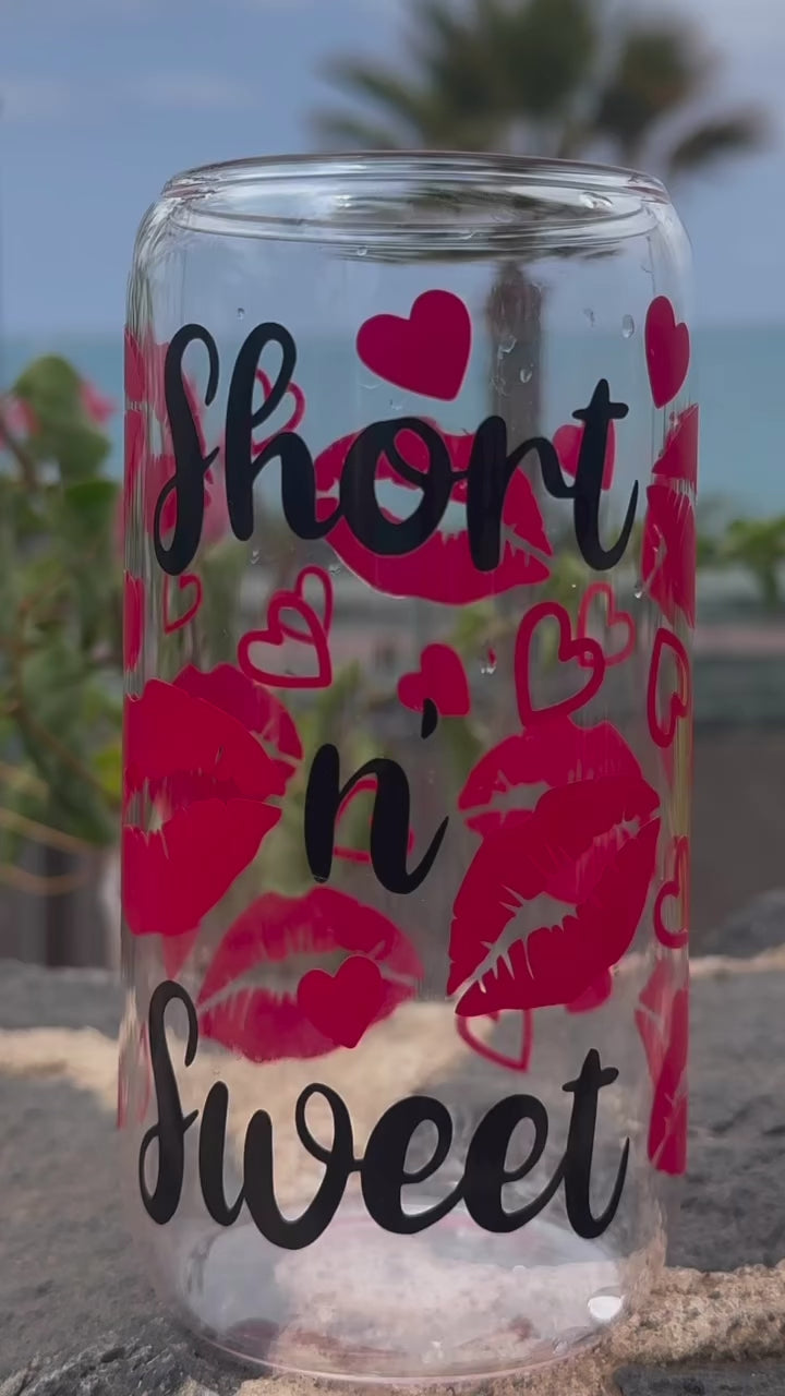 Glass can cup ASMR style with 'short n' sweet' text and red lips design on a stone surface with plants in the background
