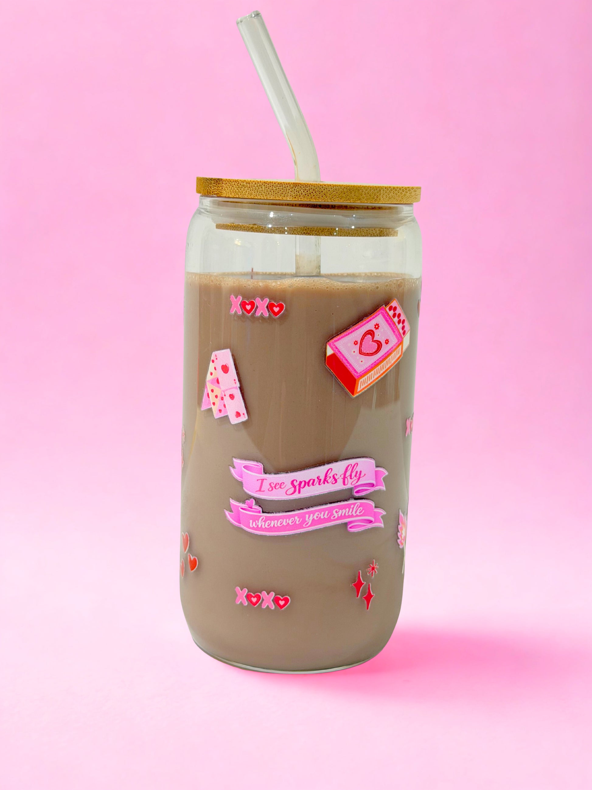 “16oz clear glass can cup with bamboo lid and glass straw, featuring a pink Valentine’s design inspired by ‘Sparks Fly’ with hearts, love notes and romantic details on a pink background.”